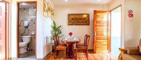 A dining area with a round table, chairs, and a vase of flowers.
