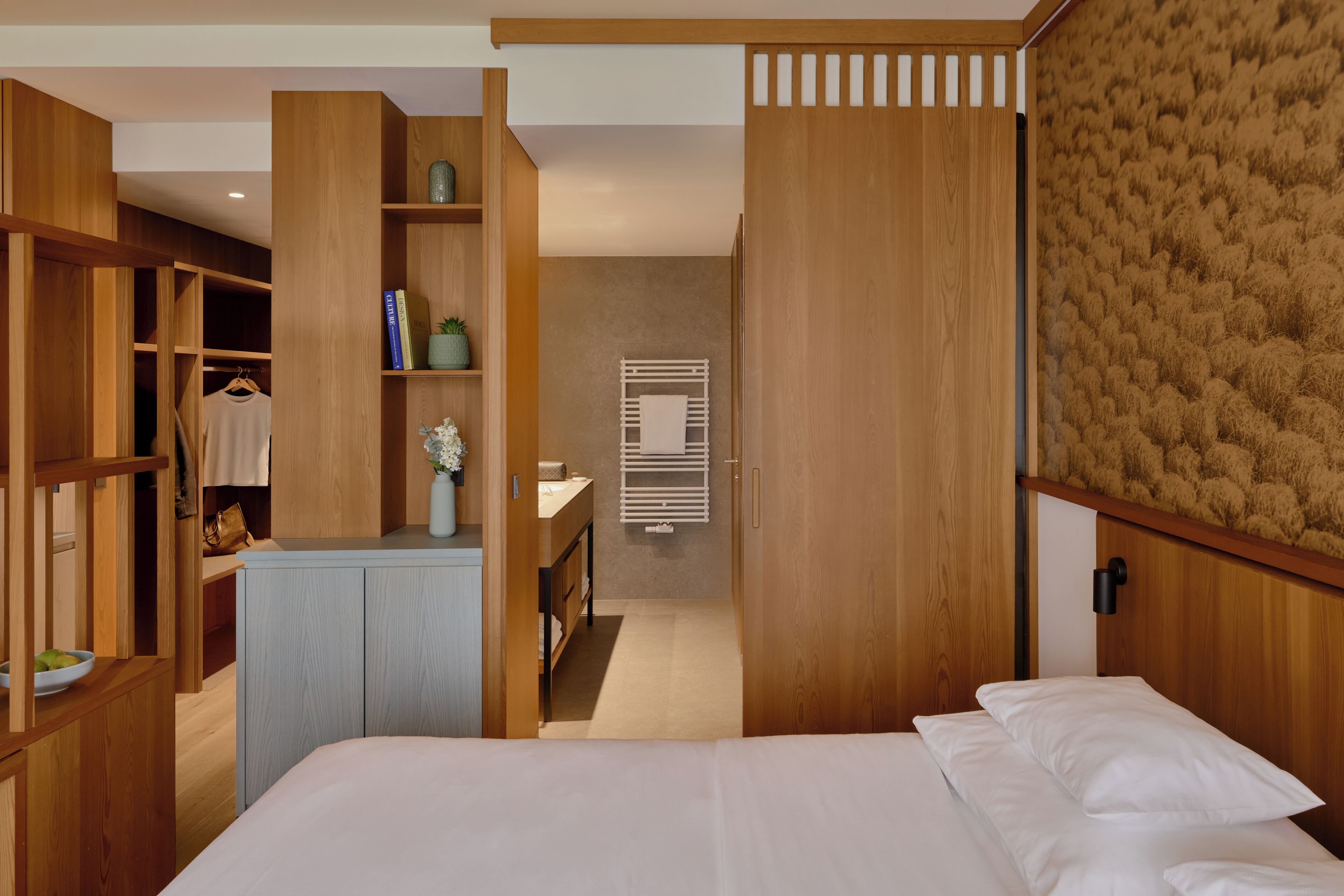 A modern bedroom with a bed, a wardrobe, and a vanity area.
