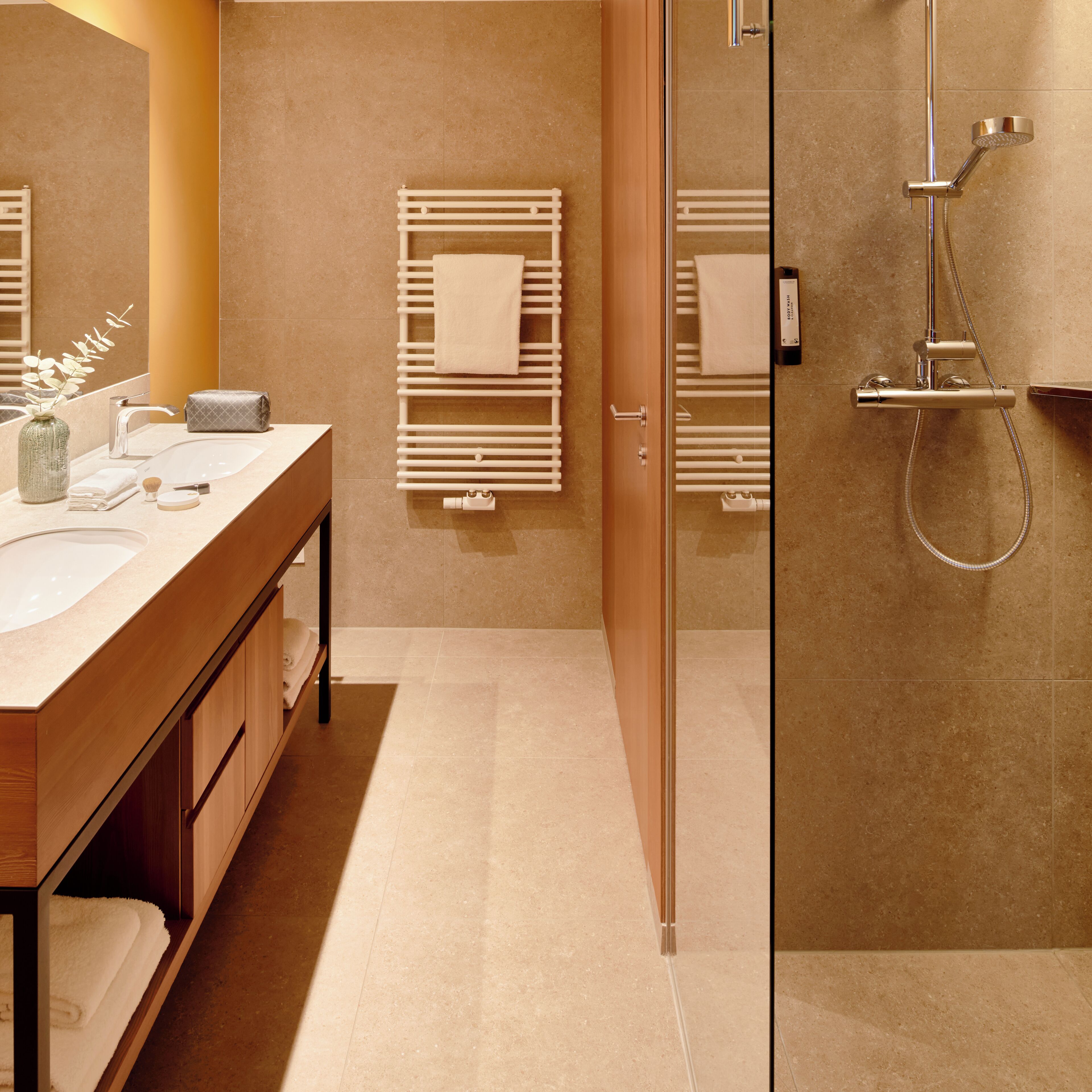 A modern bathroom with a glass shower enclosure, a wooden vanity with a sink, and a towel rack.