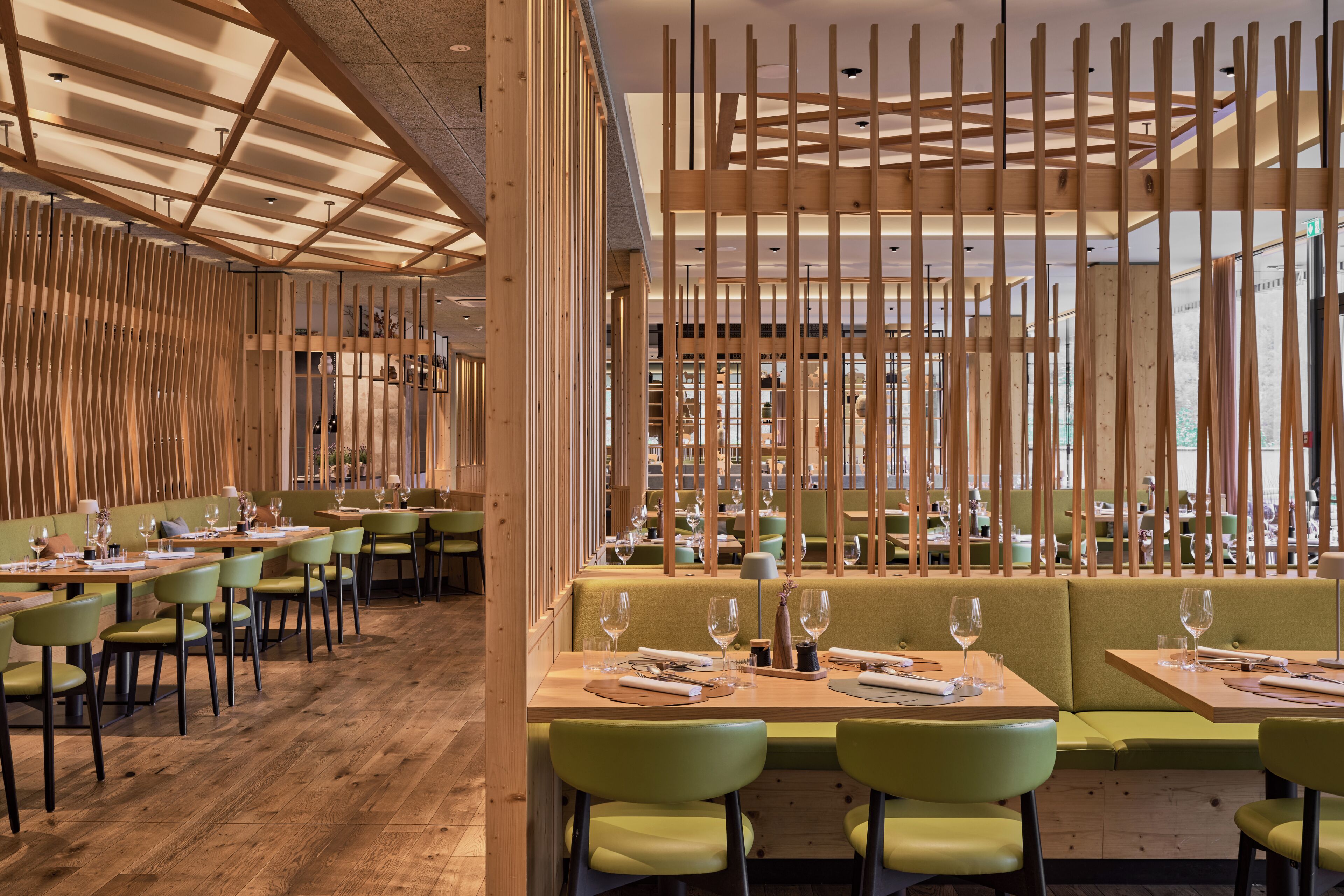 Un restaurante con paneles de madera, asientos tapizados en verde y mesas de madera.