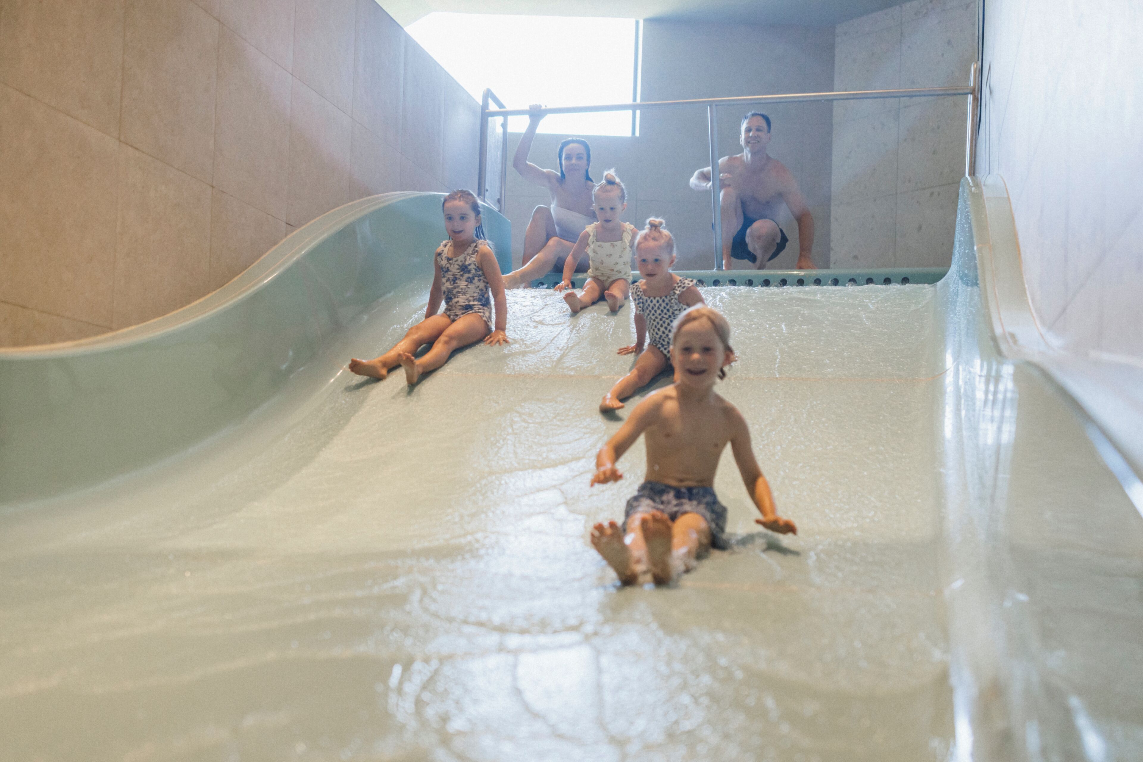 Des enfants glissent sur un toboggan aquatique dans une zone de piscine.