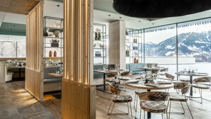 Un restaurante moderno con detalles de madera, mesas y sillas redondas, y vistas a montañas.