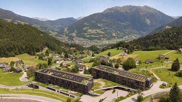 A modern building complex with a parking area and a view of a mountainous landscape.