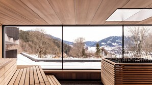 Un interior moderno con un banco de madera y una zona de estar con vistas a montañas nevadas.