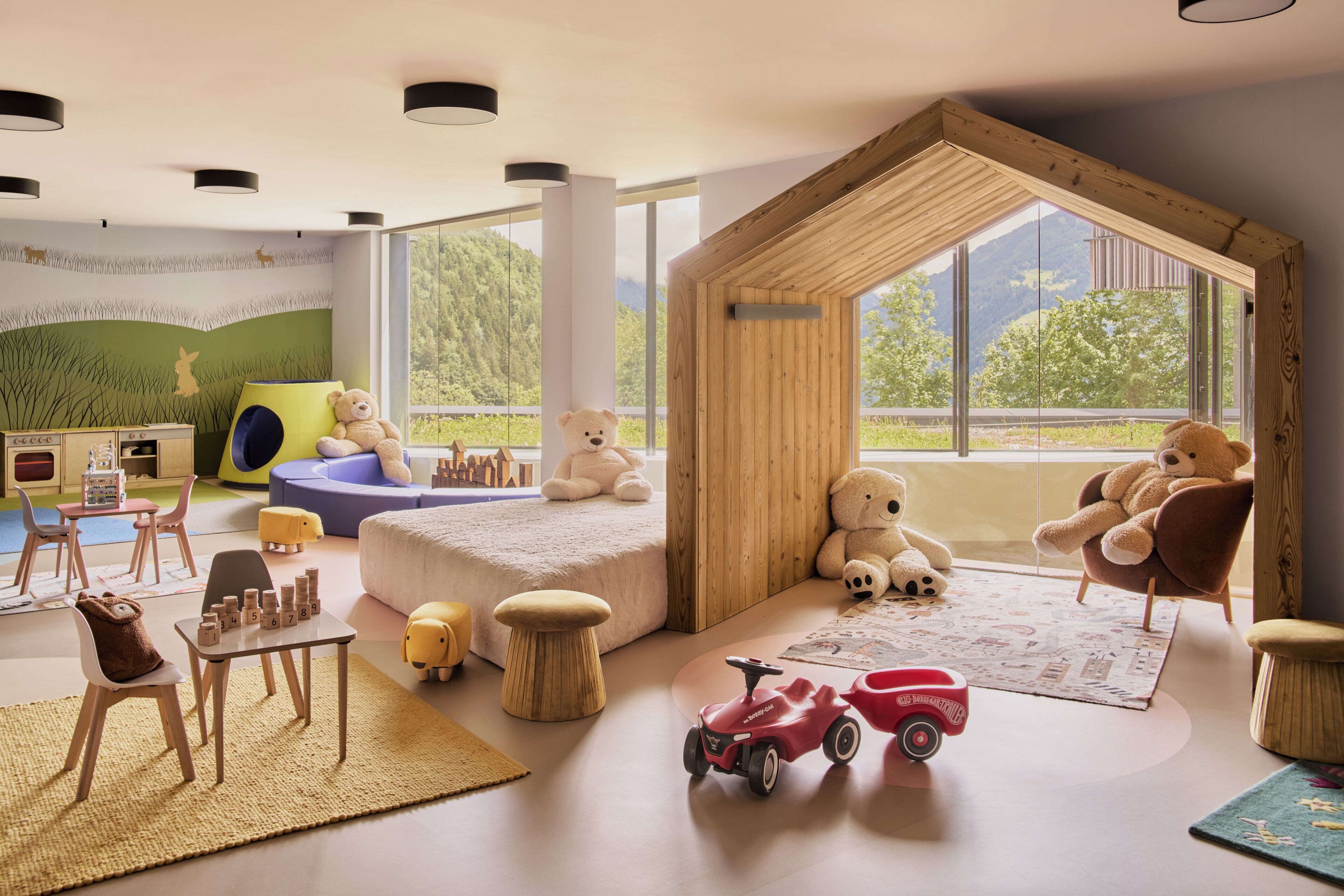 A children's playroom with a large window, wooden playhouse, and various toys.