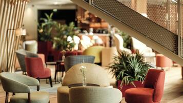 A modern interior with a staircase, seating areas, and indoor plants.