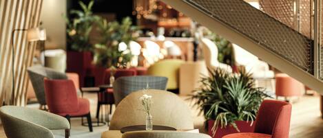 A modern interior with a staircase, seating areas, and indoor plants.