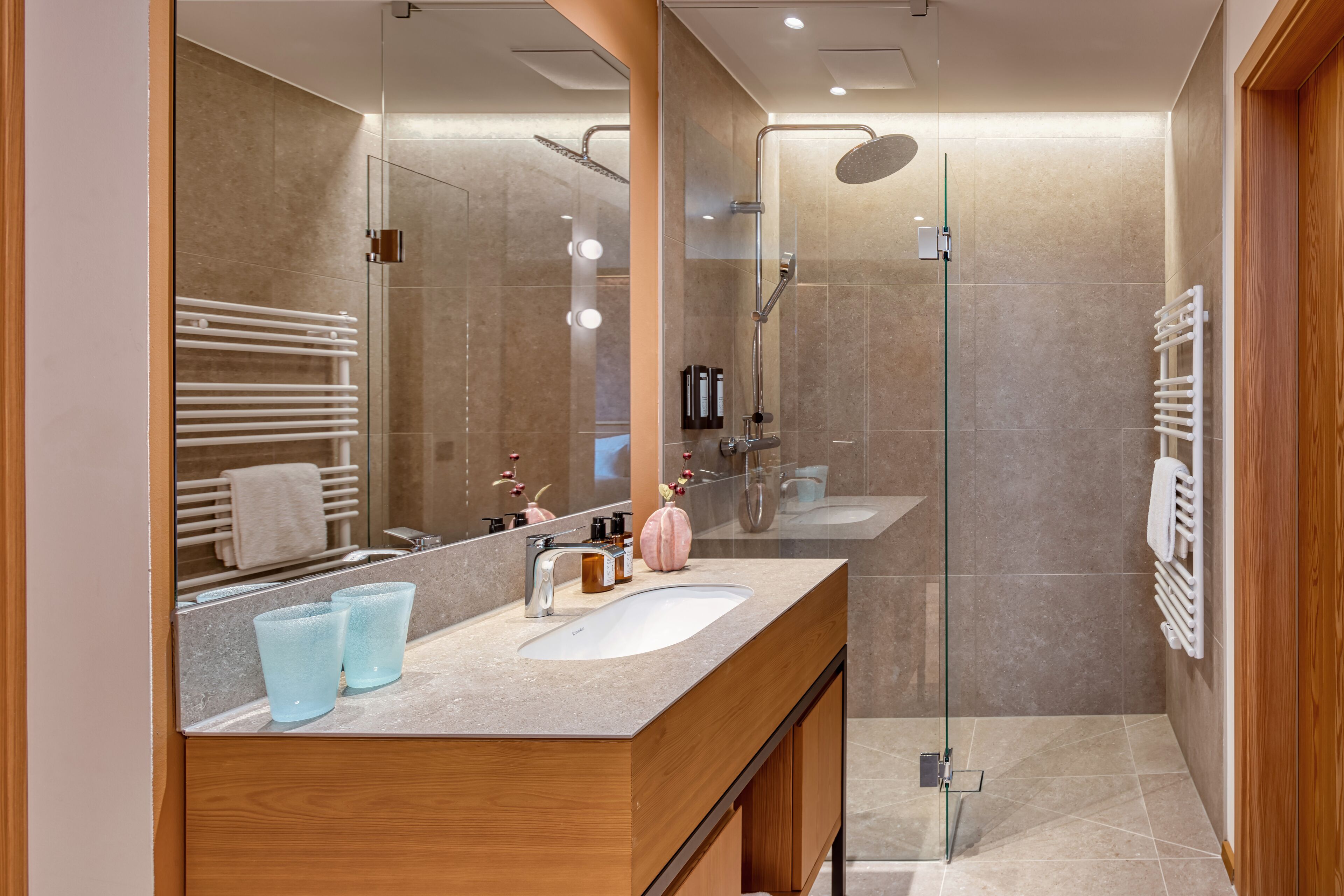 A modern bathroom with two sinks, a glass shower enclosure, and a large mirror.