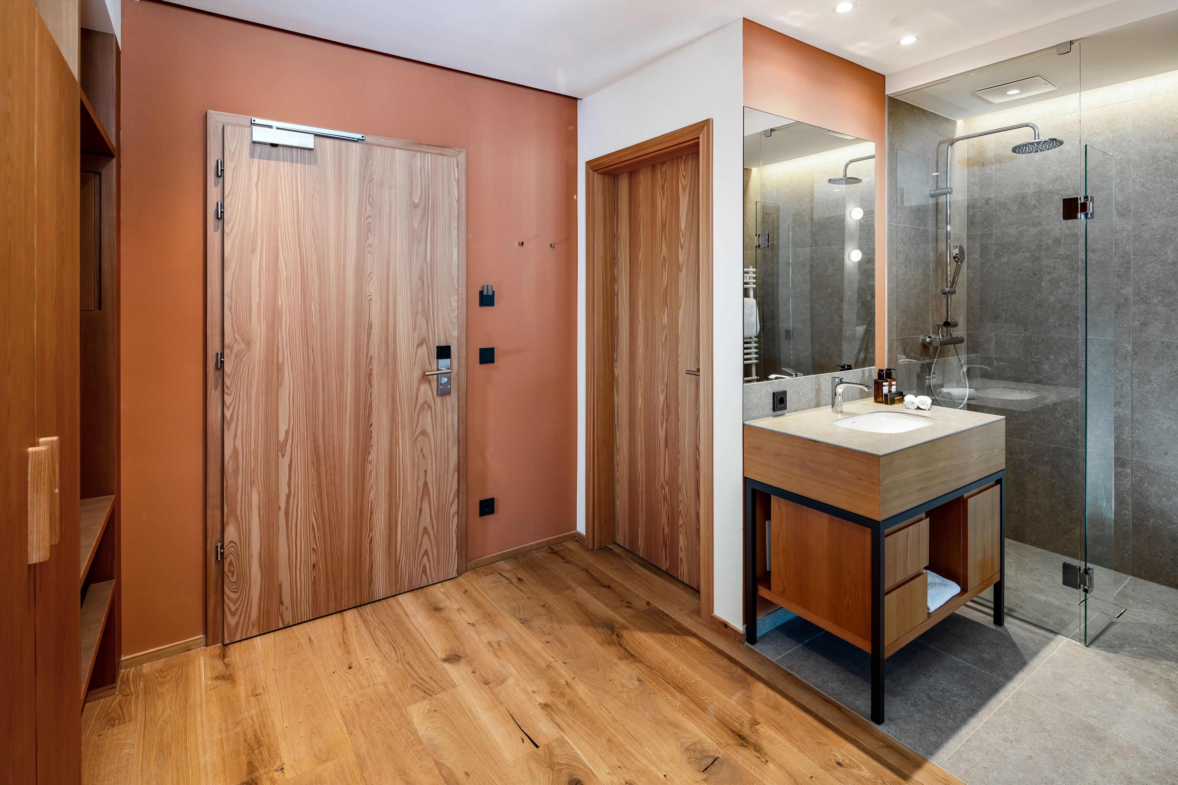 A modern bathroom with wooden doors, a glass shower enclosure, and a wooden vanity with a sink.