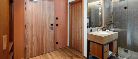 A modern bathroom with wooden doors, a glass shower enclosure, and a wooden vanity with a sink.