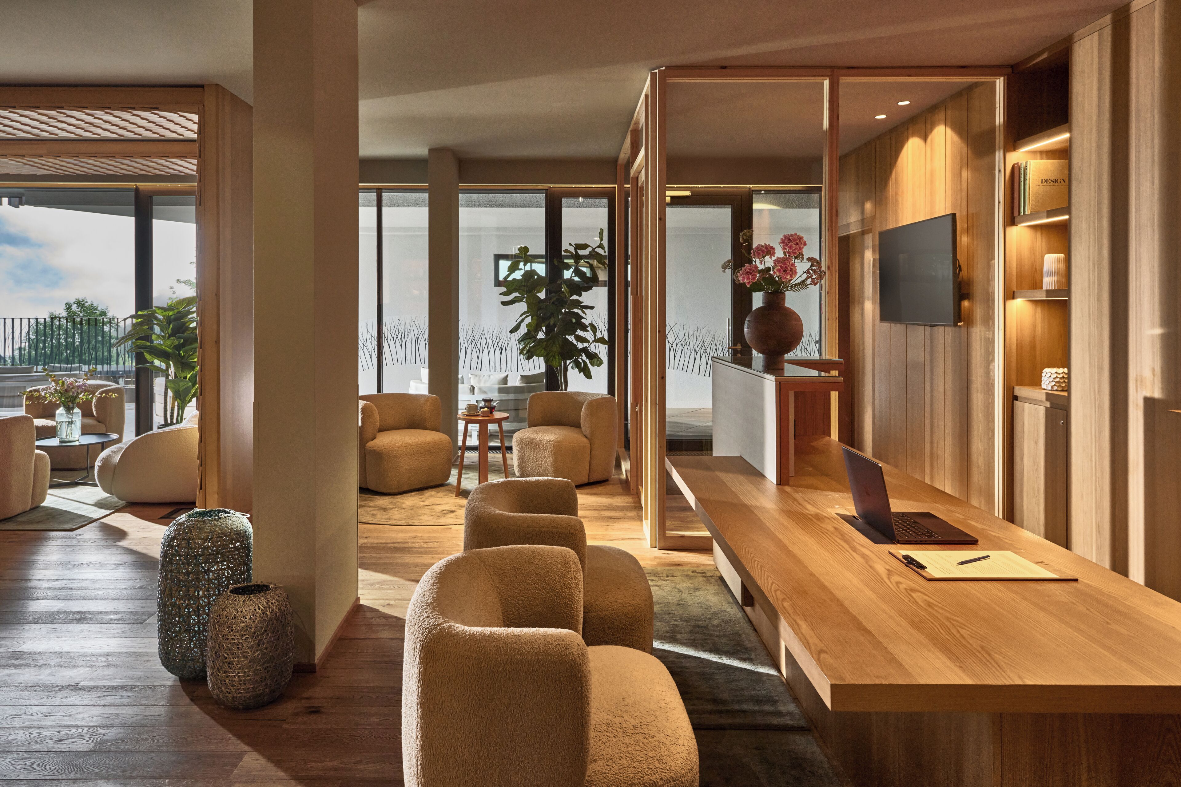 Un interior modern amb un taulell de recepció de fusta, zones d'estar confortables i un gran finestral que ofereix una vista.