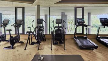 Un gimnasio con cintas de correr, elípticas y una colchoneta para yoga.