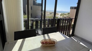 A balcony with a table and a basket of fruit, overlooking a coastal landscape.