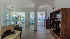 A spacious living area with a view of the sea, a glass table, and a wooden bookshelf. - Villa La Palmera with private pool and fantastic views (Salobreña)