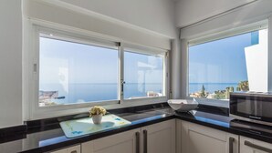A kitchen with two large windows, a black countertop, and white cabinets. - Villa La Palmera with private pool and fantastic views (Salobreña)