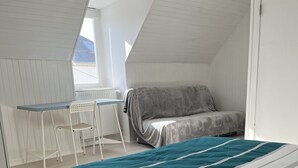Een slaapkamer met een bed, een stoel, een tafel en een bank.