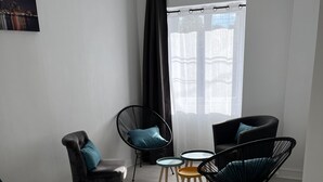 Een moderne woonkamer met een bank, twee fauteuils, een salontafel en een televisie.