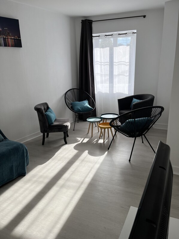 A modern living room with a sofa, two armchairs, a coffee table, and a TV.