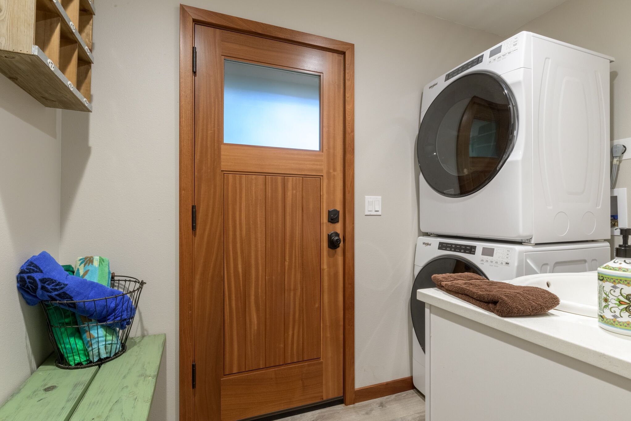 Un área de lavandería con una puerta de madera, una lavadora y un tendedero.