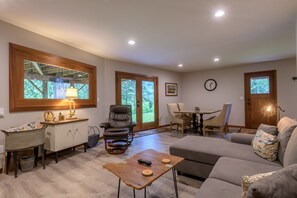 Un salon spacieux doté d’une grande fenêtre, d’une cheminée, d’un coin repas et d’un espace salon confortable.