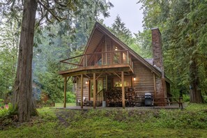 Une cabane en bois dotée d’un balcon, entourée d’une forêt dense.