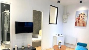 Un salon moderne avec un téléviseur à écran plat, une table basse et un canapé bleu.