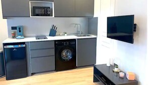 Une cuisine compacte équipée d’un four à micro-ondes, d’un évier, d’un lave-vaisselle et d’une machine à laver.