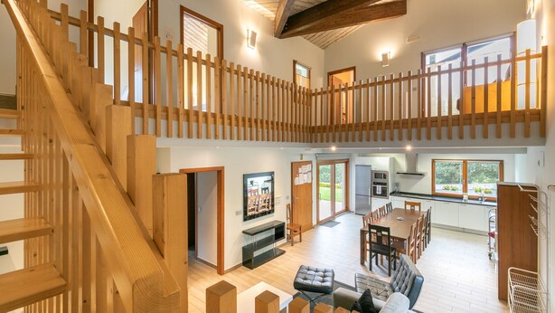 Una vivienda espaciosa de varios niveles, con escalera de madera, comedor y cocina.