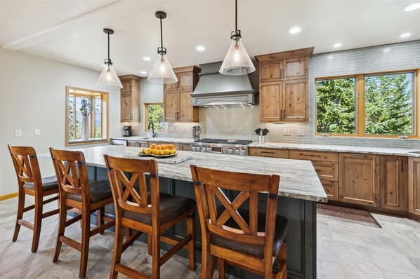 Una cocina moderna con una isla grande, armarios de madera e iluminación colgante.