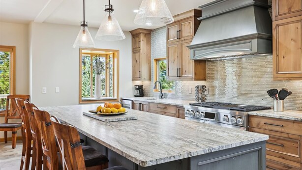 Une cuisine spacieuse dotée d’un grand îlot central, de meubles en bois et d’une cuisinière moderne.