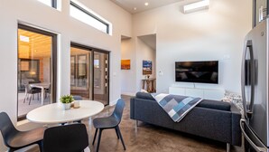 Una sala de estar moderna con un sofá, un televisor y un comedor con sillas y una mesa.