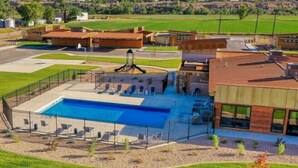 Un edificio moderno con piscina, asientos al aire libre y un parque infantil.