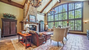 A spacious living room with a stone fireplace, large windows, and a high ceiling. - 8,000+ Sq Ft Breck Ski Home, Hot Tub, Theater, Pool Table, Sleeps 14 (Breckenridge)