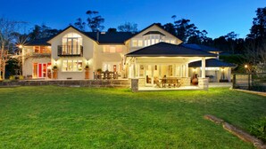 A large, two-story house with a covered patio and a well-maintained lawn.