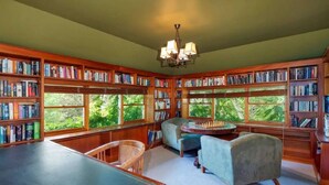 A library with bookshelves, a chess table, and two armchairs.