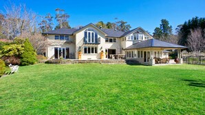 A large two-story house with a spacious backyard, a covered patio, and a well-maintained lawn.