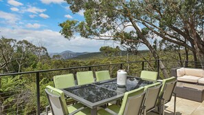 A glass-top table with green chairs and a wicker sofa, overlooking a mountainous landscape. - Aisling View in Blackheath (Blackheath)