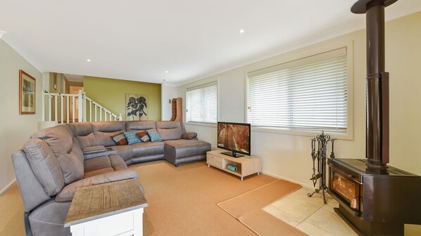 A living room with a sectional sofa, a flat-screen TV, a fireplace, and a staircase leading to another level. - Aisling View in Blackheath (Blackheath)