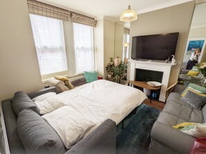 Um quarto moderno com uma cama grande, um sofá, uma TV e uma lareira.