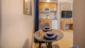 Un espace de vie compact comprenant un coin repas, une kitchenette et un téléviseur.