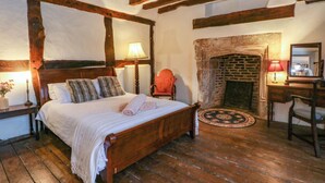 A traditional room with a wooden bed, a fireplace, and a desk with a mirror. - Y Fferm (Mold)