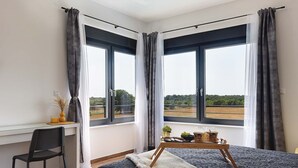 A bedroom with a bed, a desk, and two windows with curtains. - Villa Tika in Jadreski (Jadreski)