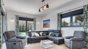 A modern living room with a sectional sofa, two armchairs, a coffee table, and large windows with curtains. - Villa Tika in Jadreski (Jadreski)