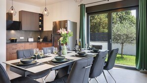 A modern kitchen with dark cabinets, a built-in oven, and a dining area with a table set for six. - Villa Tika in Jadreski (Jadreski)