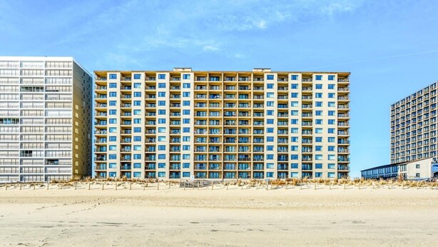 A multi-story hotel with a uniform facade, balconies, and a sandy beachfront. - Marigot Beach 303 2 Bedroom Condo by RedAwning (Ocean City)