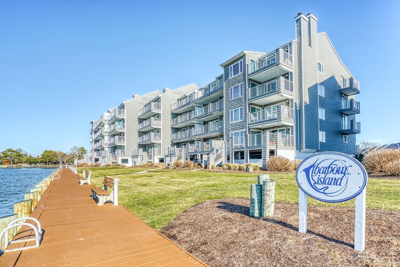 Un edificio residencial de varios pisos con balcones, una pasarela de madera que lleva al agua, y un letrero que dice 'Chabou Island'.
