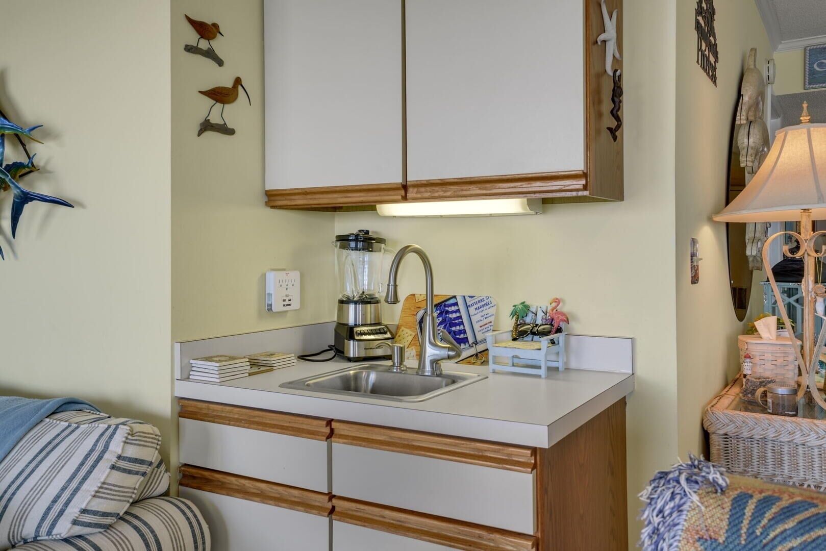 A compact kitchen with a built-in sink, a blender, and a small island with a lamp.