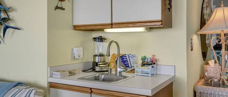 A compact kitchen with a built-in sink, a blender, and a small island with a lamp.