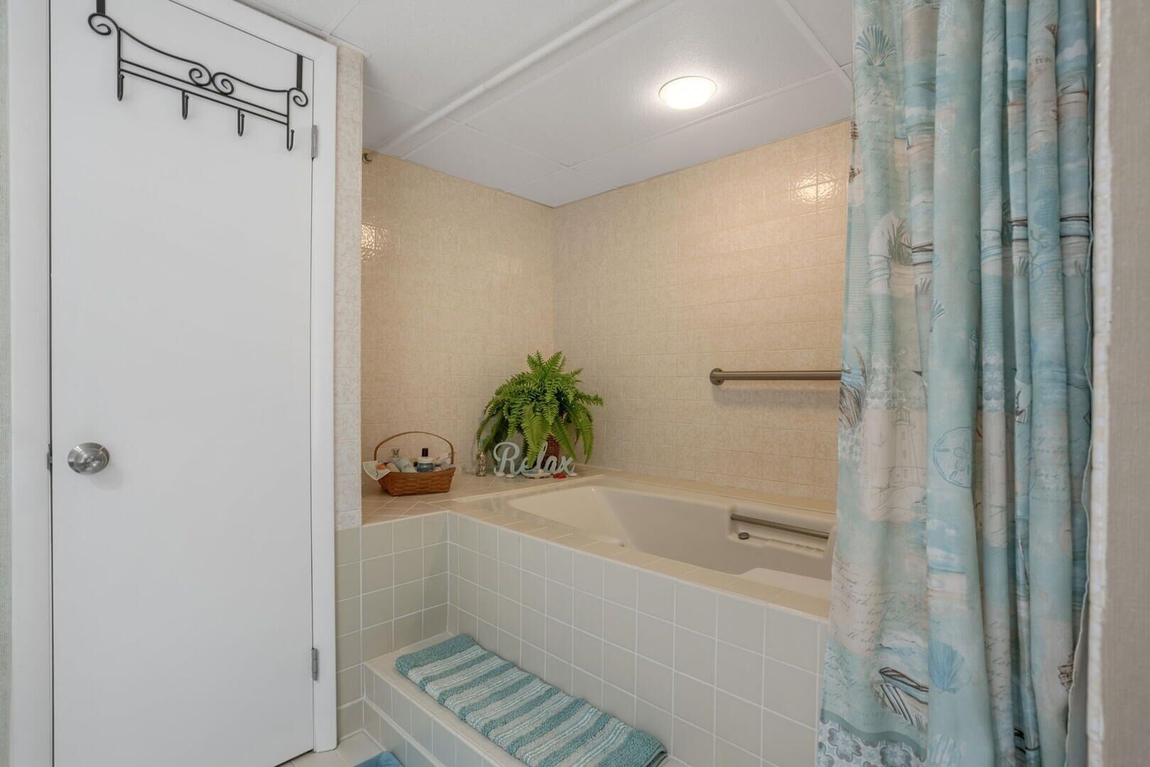 Une salle de bain comprenant une baignoire, un espace douche, un porte-serviettes et une porte dotée d’une poignée décorative.