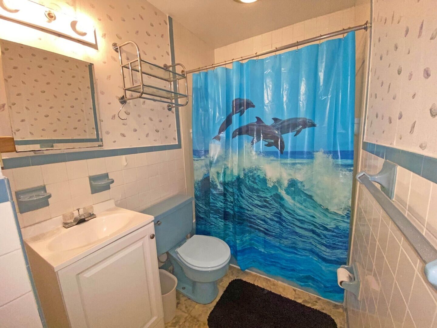 Ein Badezimmer mit Toilette, Waschbecken und einer Duschvorhang mit Delphinen.